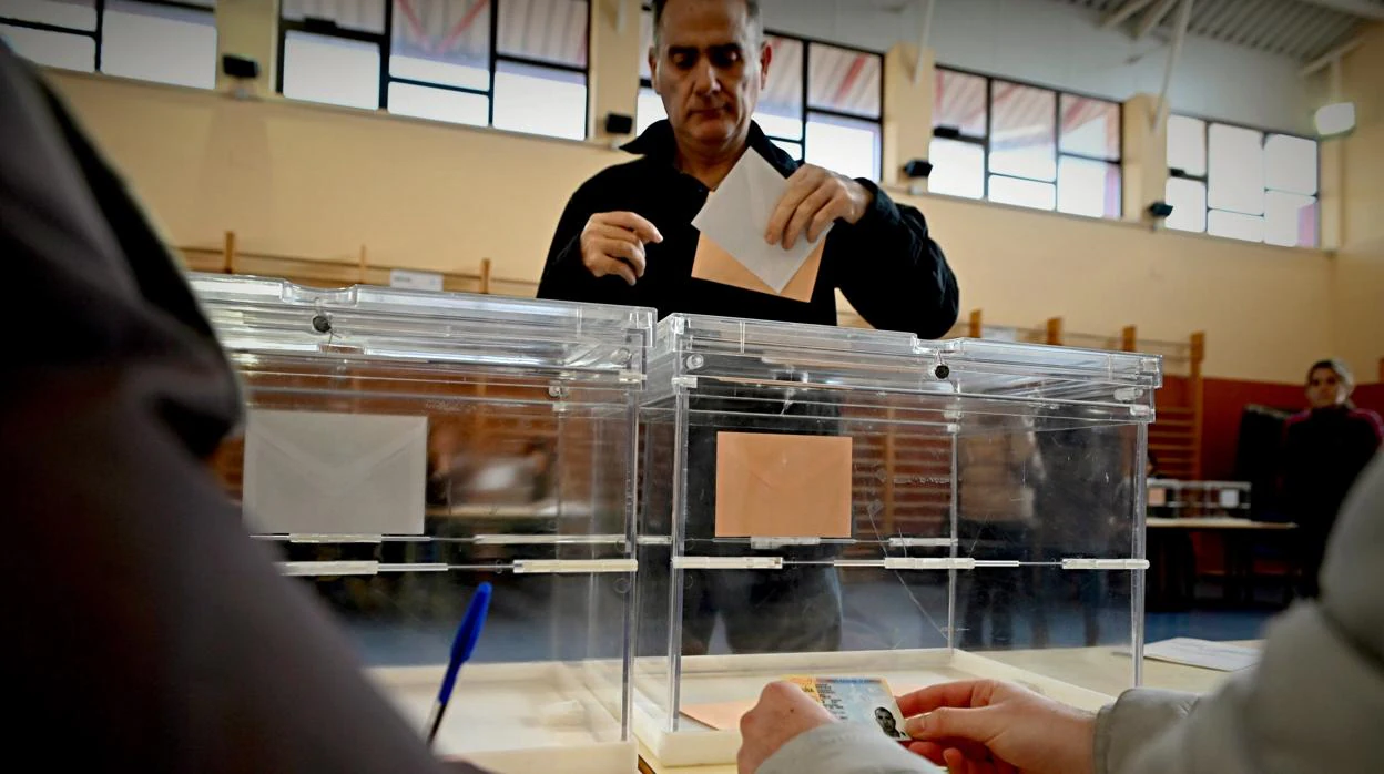 Un ciudadano deposita su voto en un colegio de Alcalá de Henares, Madrid