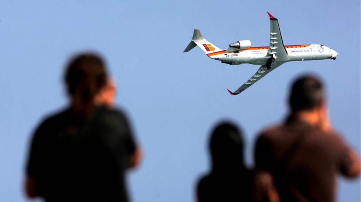 Varias personas observan el vuelo de un avión comercial