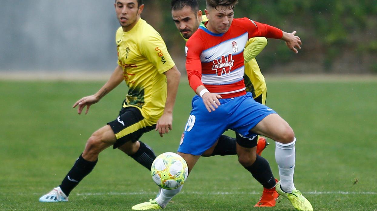 Dos jugadores del Villarrubia disputan el balón a un jugador granadino