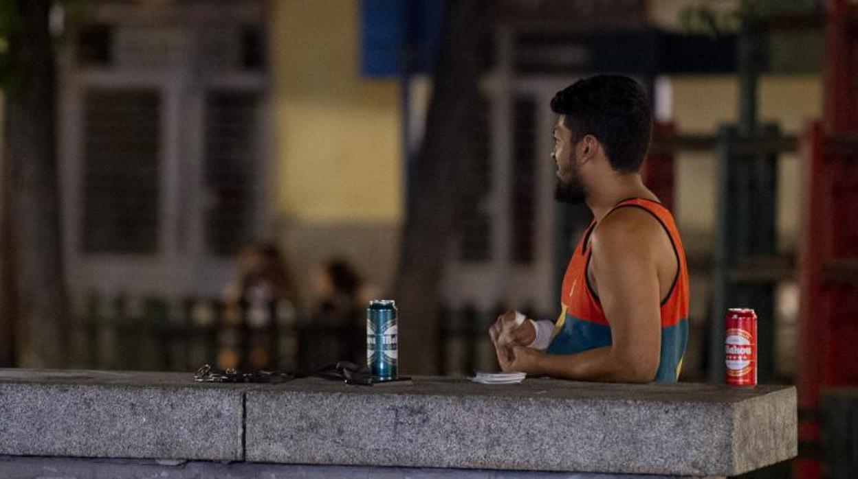 Un hombre se lía un cigarro junto a unas latas de cerveza en Malasaña