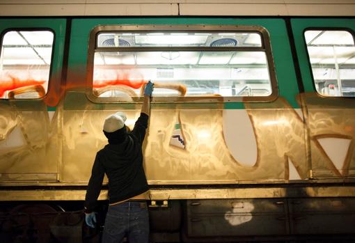 Un grafitero pinta un vagón de Metro