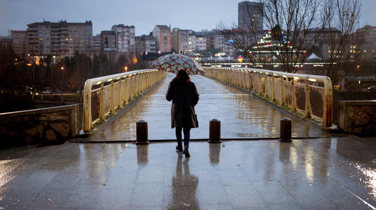 Una mujer se refugia de la lluvia en Orense