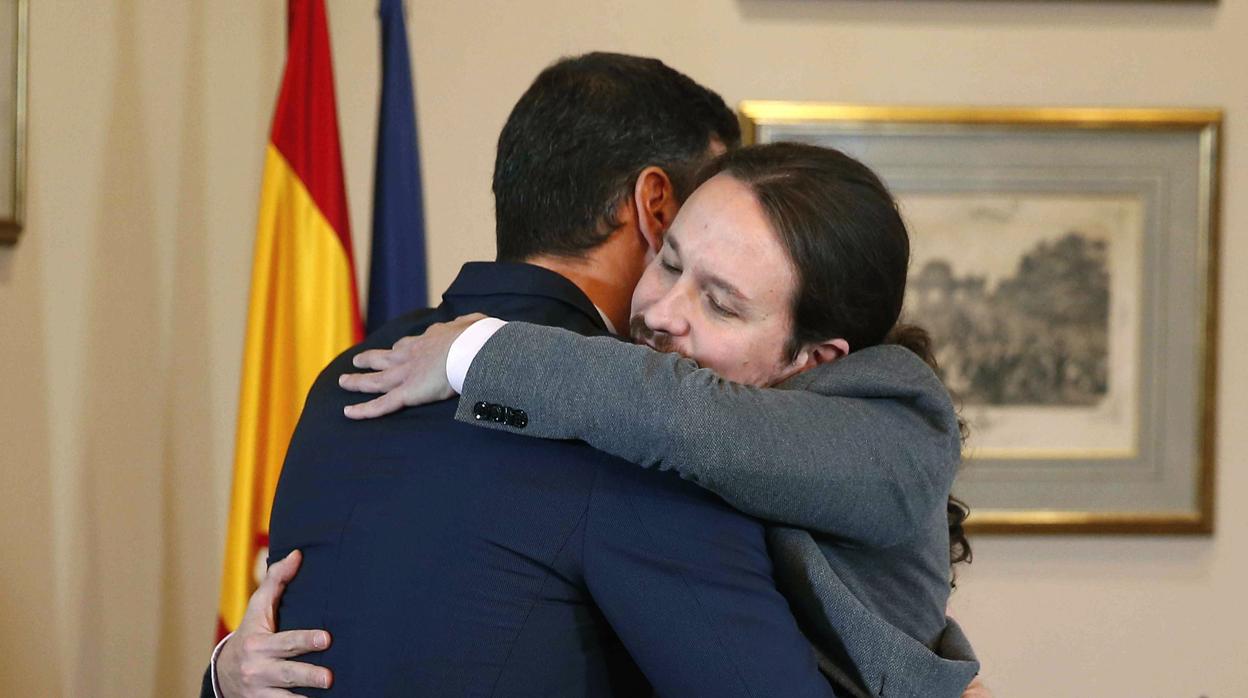 El presidente del Gobierno español en funciones, el socialista Pedro Sánchez (i), y el líder de Unidas Podemos, Pablo Iglesias, se abrazan en el Congreso tras firmar un acuerdo para la formación de un Ejecutivo, el 12 de noviembre