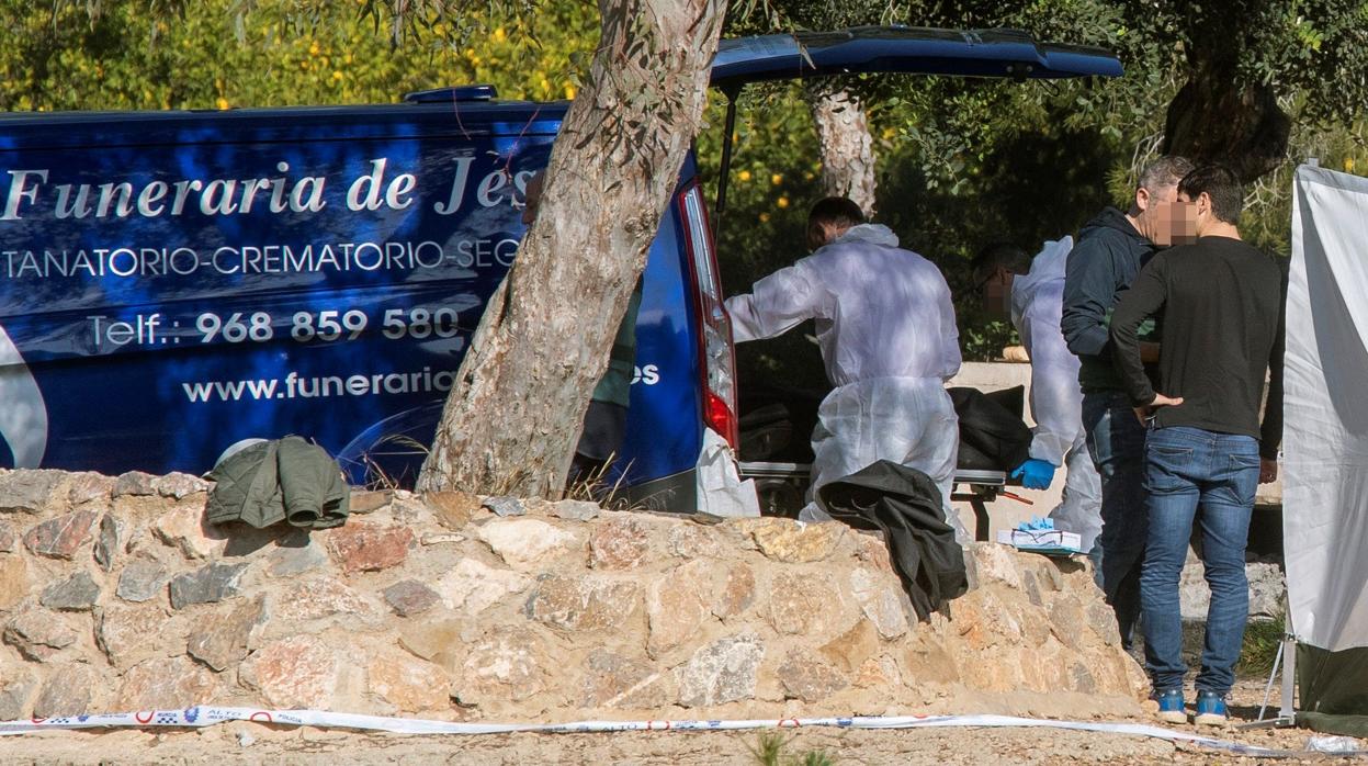 Agentes de la Guardia Civil introduciendo el cuerpo sin vida de la fallecida en el furgón de la funeraria