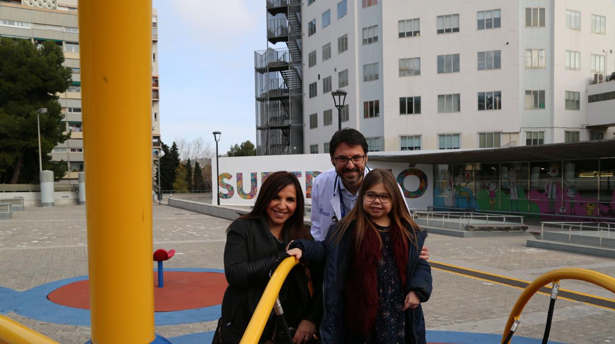 La pequeña Iria, junto a su madre, y uno de los médicos del Vall d'Hebron que la intervinieron