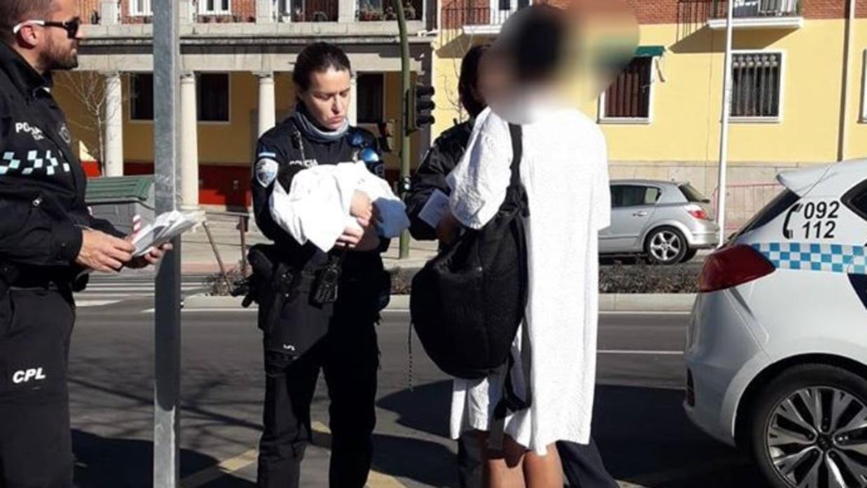 Una mujer policía sujeta en sus brazos al bebé en la Avenida de la Reconquista