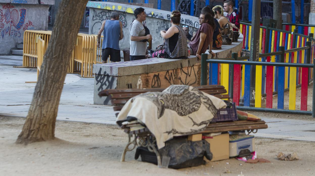 Un hombre duerme en un banco de la plaza del 2 de Mayo