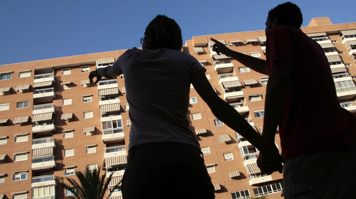 Una pareja señala un edificio de viviendas