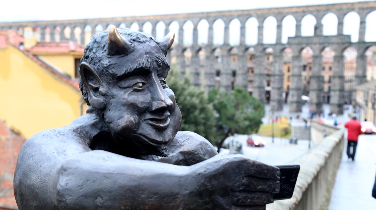 Imagen de la estatua del diablillo con el Acueducto de Segovia de fondo