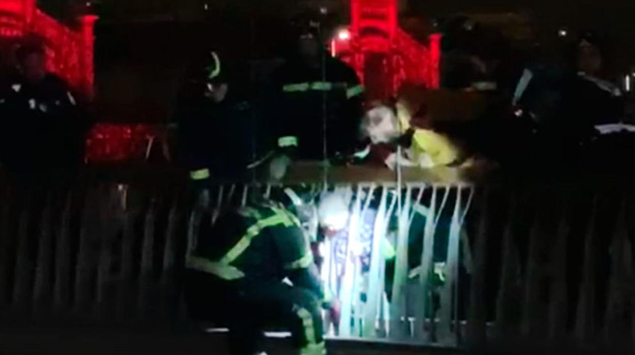 Un bombero tranquiliza al pequeño que estaba atrapado entre dos barrotes de un puente