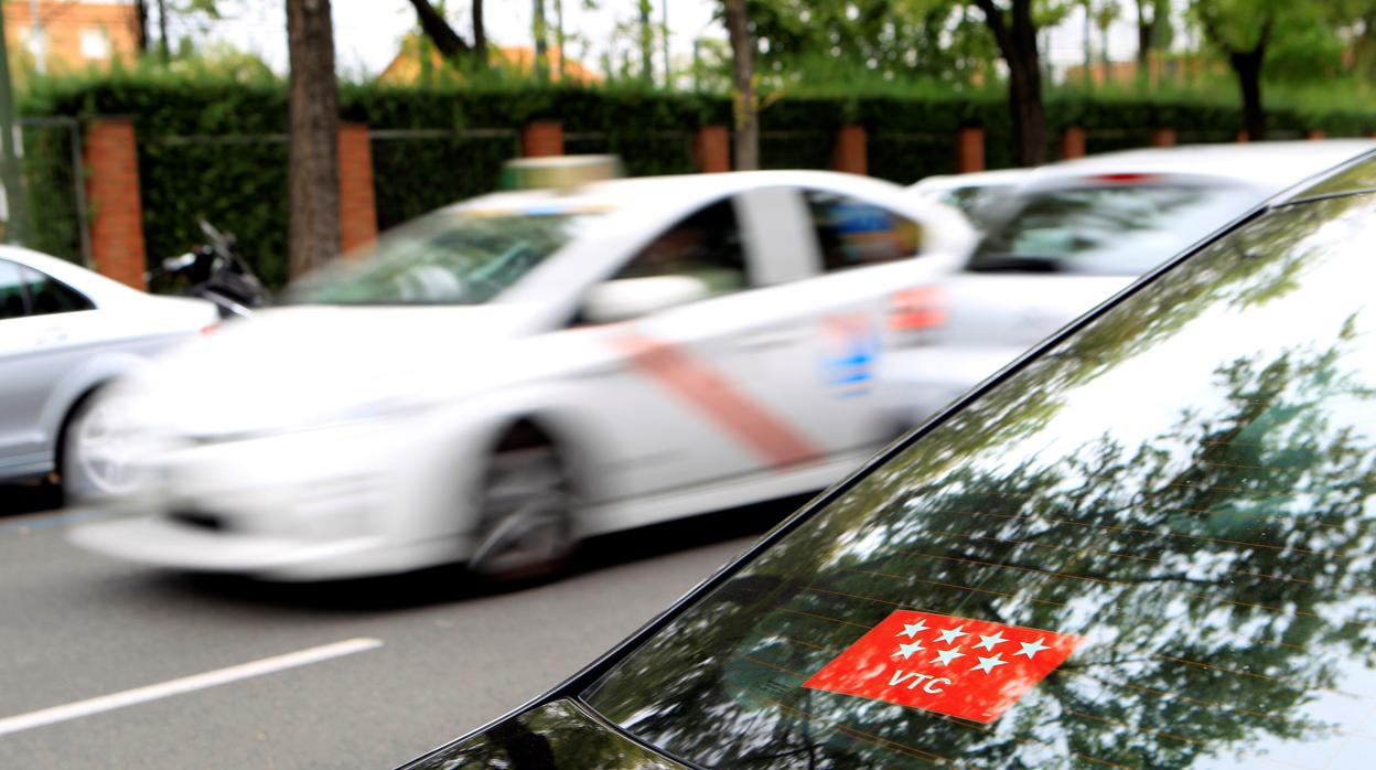 En primer plano, un vehículo VTC; detrás, un taxi, en una calle de Madrid