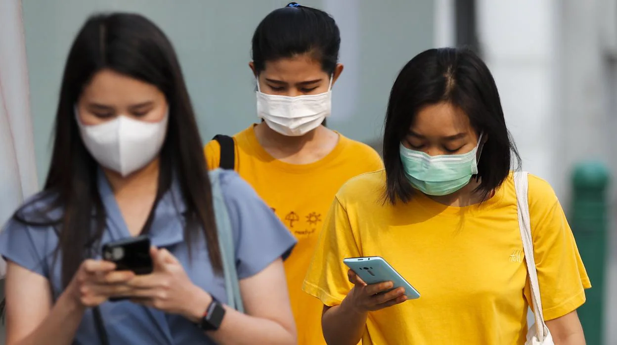 Varias personas pasean con el móvil en una zona afectada por el virus