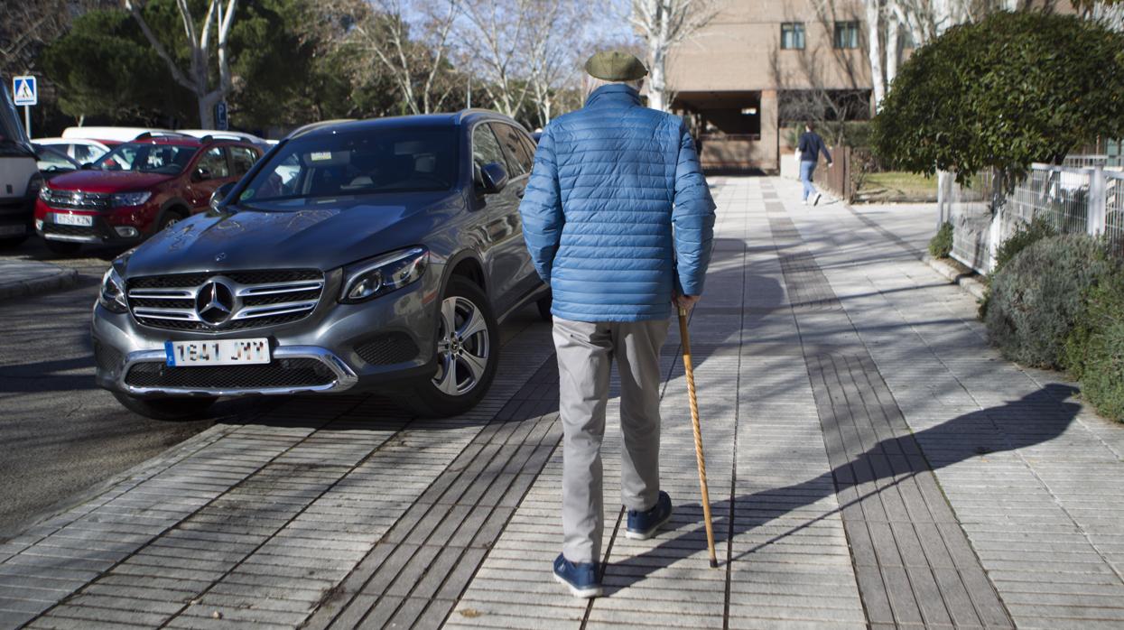 Un anciano camina apoyado en su bastón, en Madrid