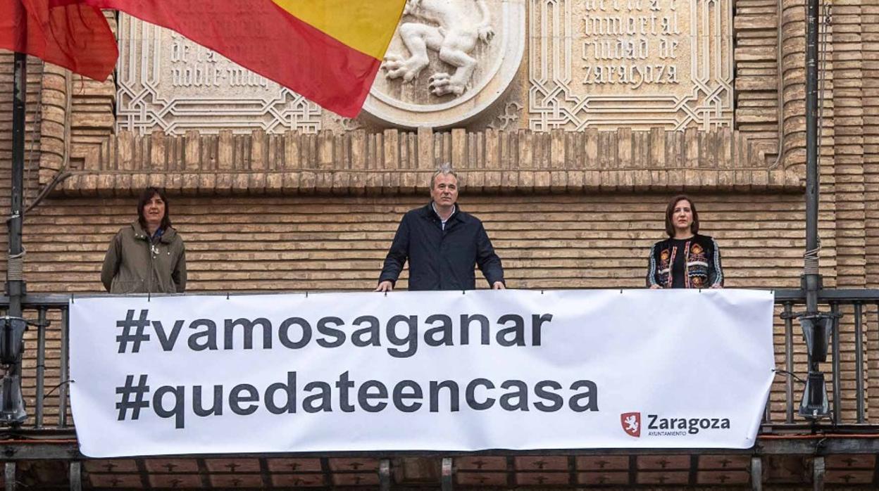 El alcalde de Zaragoza, Jorge Azcón, junto a representantes municipales, con la pancarta desplegada en el balcón de la Casa Consistorial