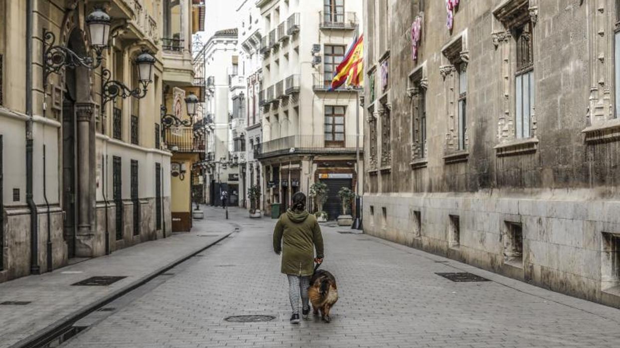 Un hombre pasea a su perro en una calle totalmente vacía de Valencia este miércoles