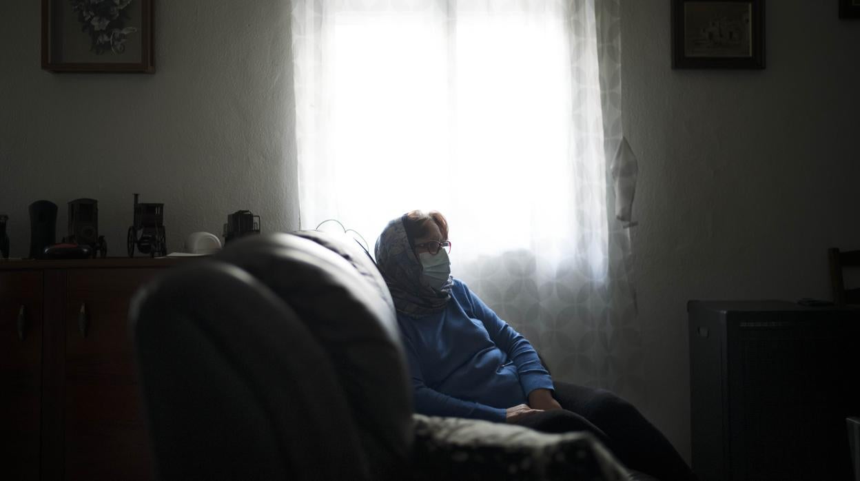 Carmen (nombre ficticio), protegida con una mascarilla, en su casa de Parla