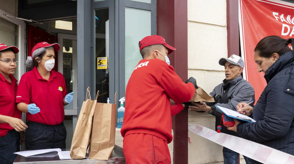 Un trabajador de Telepizza entrega un menú, ayer, a un hombre en Entrevías