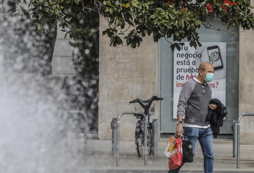 Imagen de un hombre caminando con mascarilla por las calles de Valencia