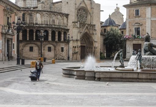 Imagen de un hombre caminando por la plaza de la Virgen de Valencia totalmente desierta