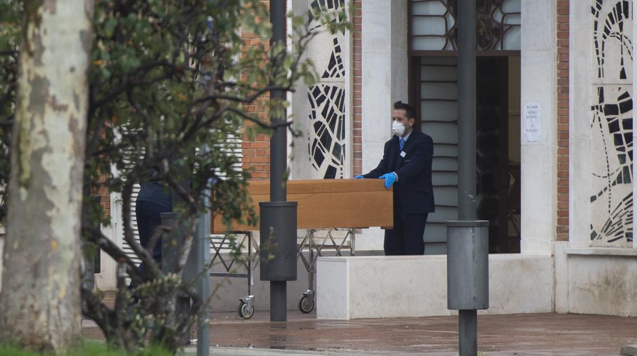 Dos trabajadores del crematorio de la Almudena trasladan, ayer, un féretro