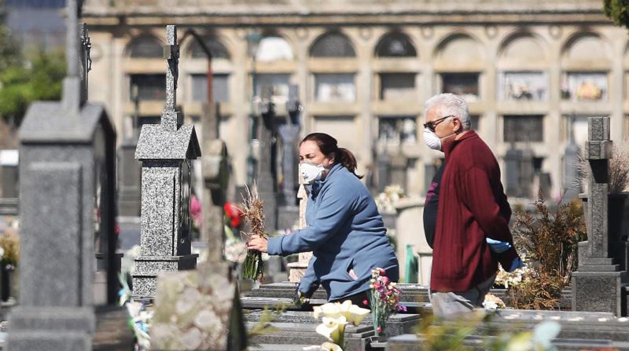 Una mujer deposita un ramo de flores en un cementerio