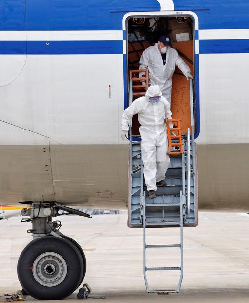 Imagen de dos operarios bajando del avión de carga con 65 toneladas de material sanitario