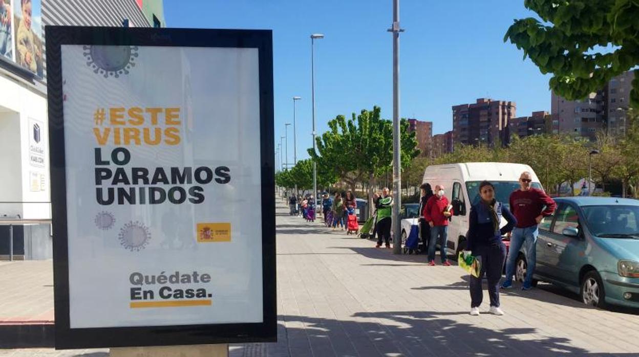 Consumidores haciendo cola a distancia prudencial para comprar en un supermercado, este viernes en Alicante