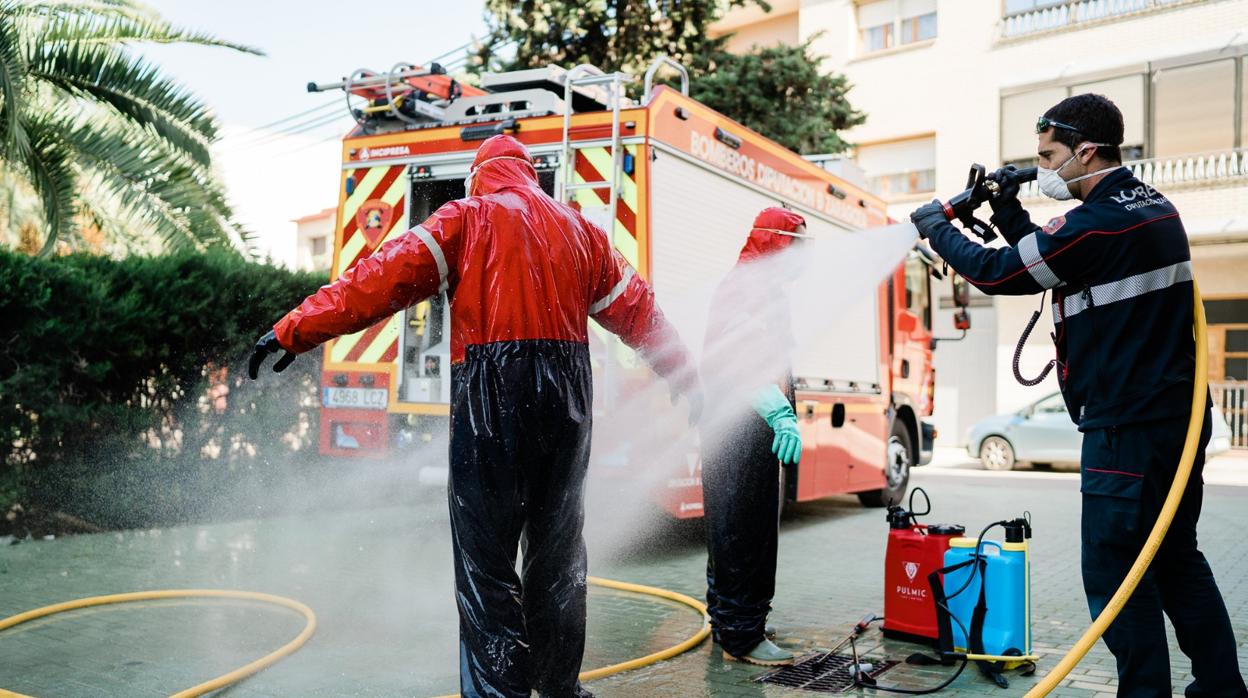 Bomberos desinfectando sus buzos durante los trabajos realizados en la residencia municipal de Caspe