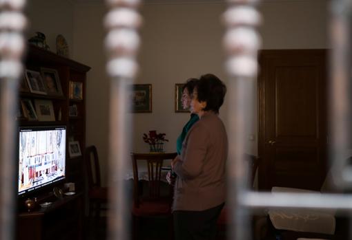 Imagen de dos mujeres siguiendo la misa desde sus casa en Villar del Arzobispo