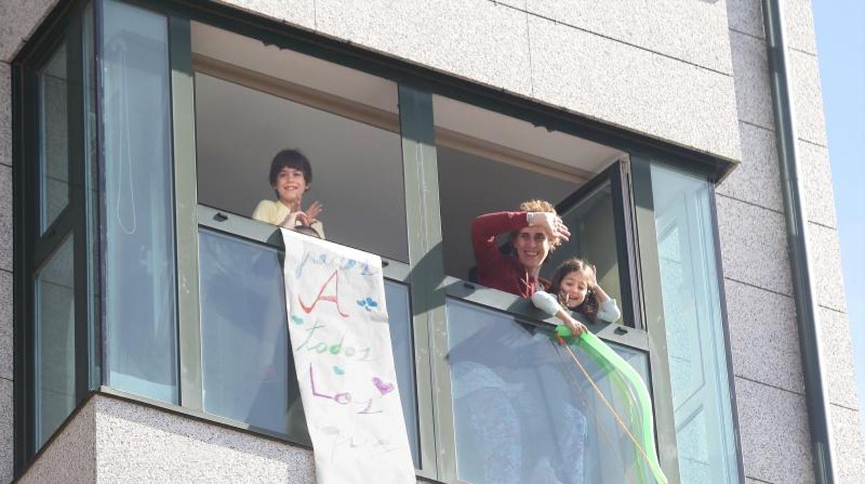 Dos niños, con su madre, asomados a la ventana de su vivienda en Santiago