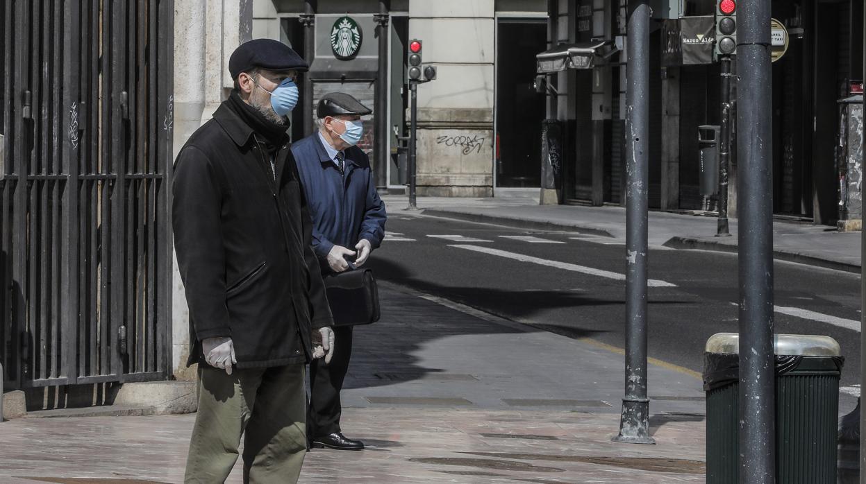 Dos hombres se protegen con mascarilla en el centro de Valencia