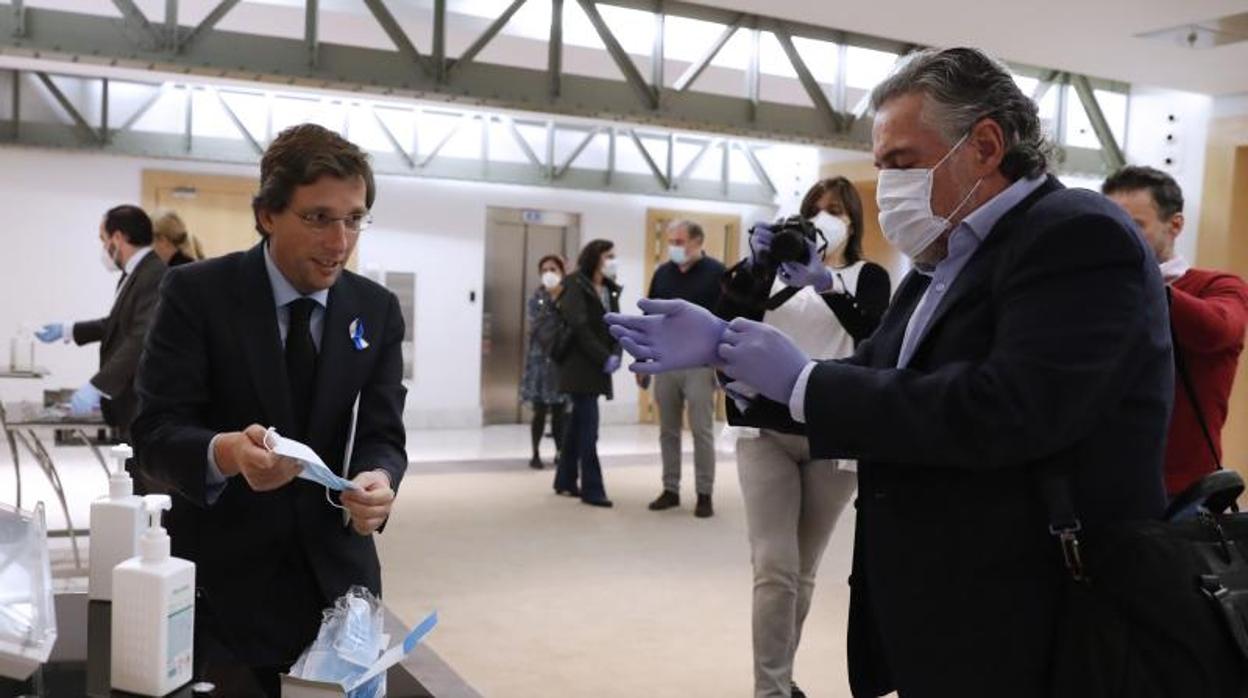 José Luis Martínez-Almeida se pone la mascarilla junto a Pepu Hernández, a la entrada del pleno