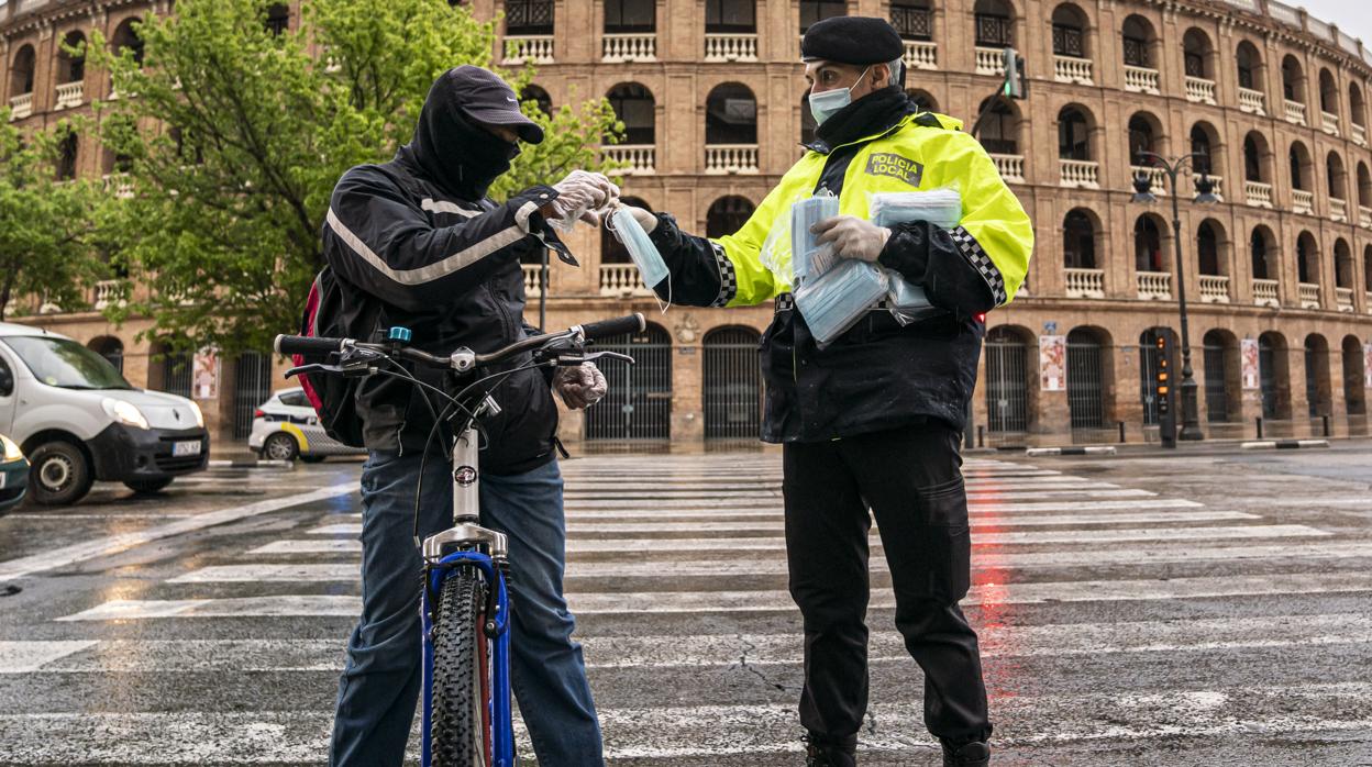 Imagen de archivo de un ciclista recogiendo una mascarilla para protegerse del coronavirus