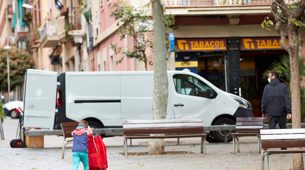 Un niño empuja un carro de la compra en una calle de Barcelona