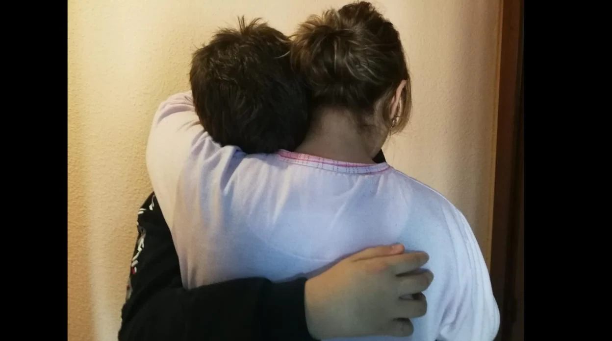 Uno de los hijos abraza a su madre en su casa este viernes