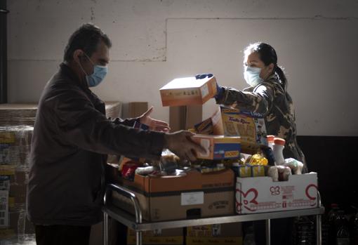 Dos voluntarios de la parroquia organizan los alimentos recibidos