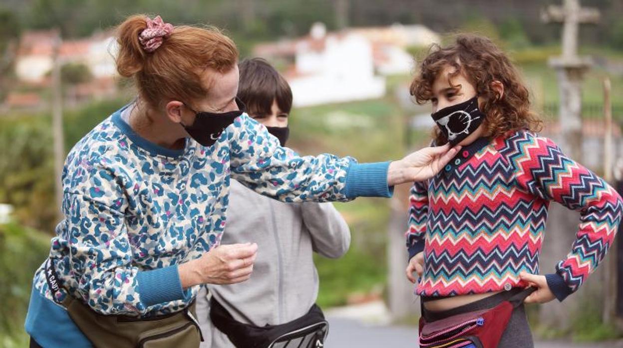 Una madre coloca la mascarilla a sus hijos durante una salida del hogar