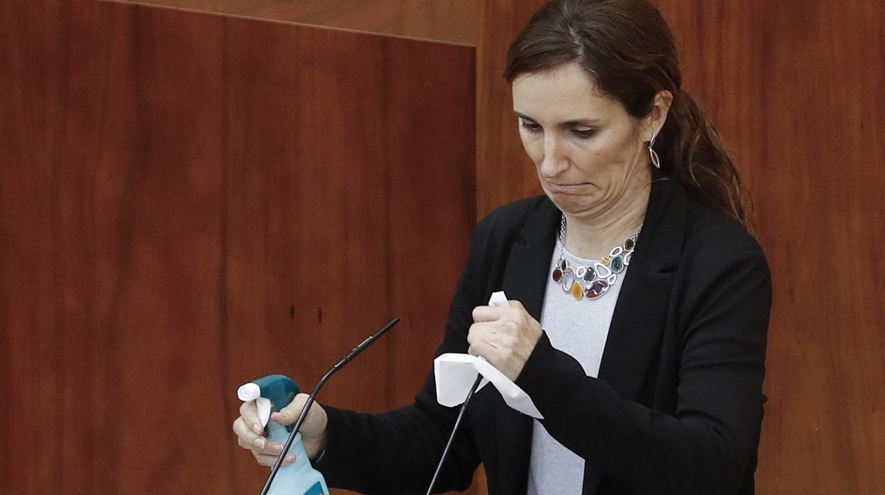 La diputada Mónica García (Más Madrid) desinfecta el atril