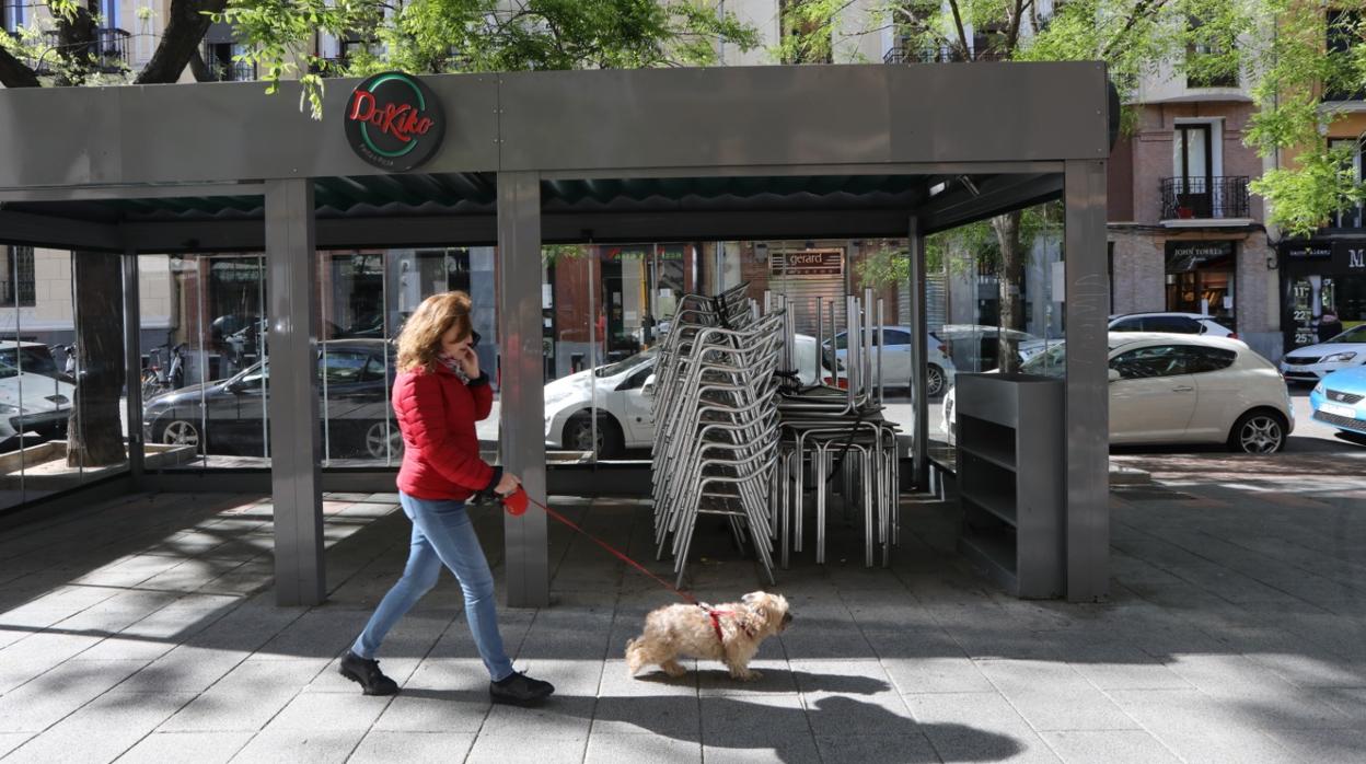 Una mujer pasa junto a una terraza cerrada de un bar en Madrid