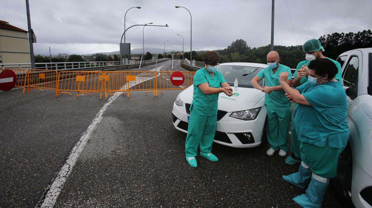 Un grupo de sanitarios se lava las manos con desinfectante ayer, en la carretera de acceso a Portugal