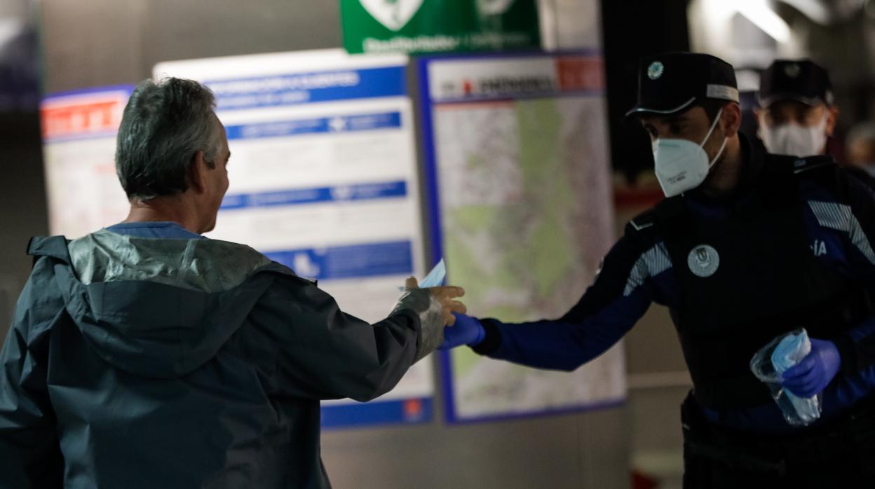 Agentes de la Policía Municipal de Madrid reparten mascarillas a los viajeros en la estación de metro de Sol