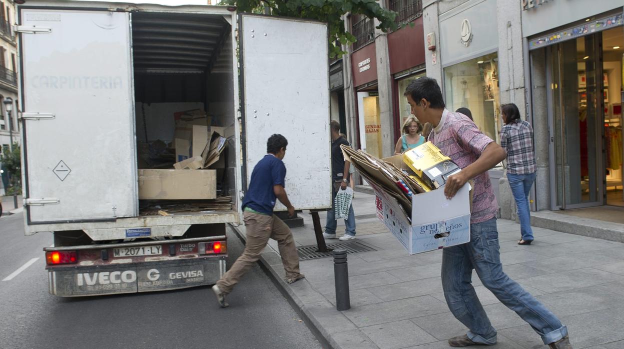 Dos personas cargan a toda prisa el cartón desechado por un comercio