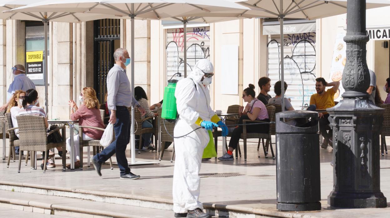 Imagen de un operario desinfectando una zona con terrazas abiertas en Valencia