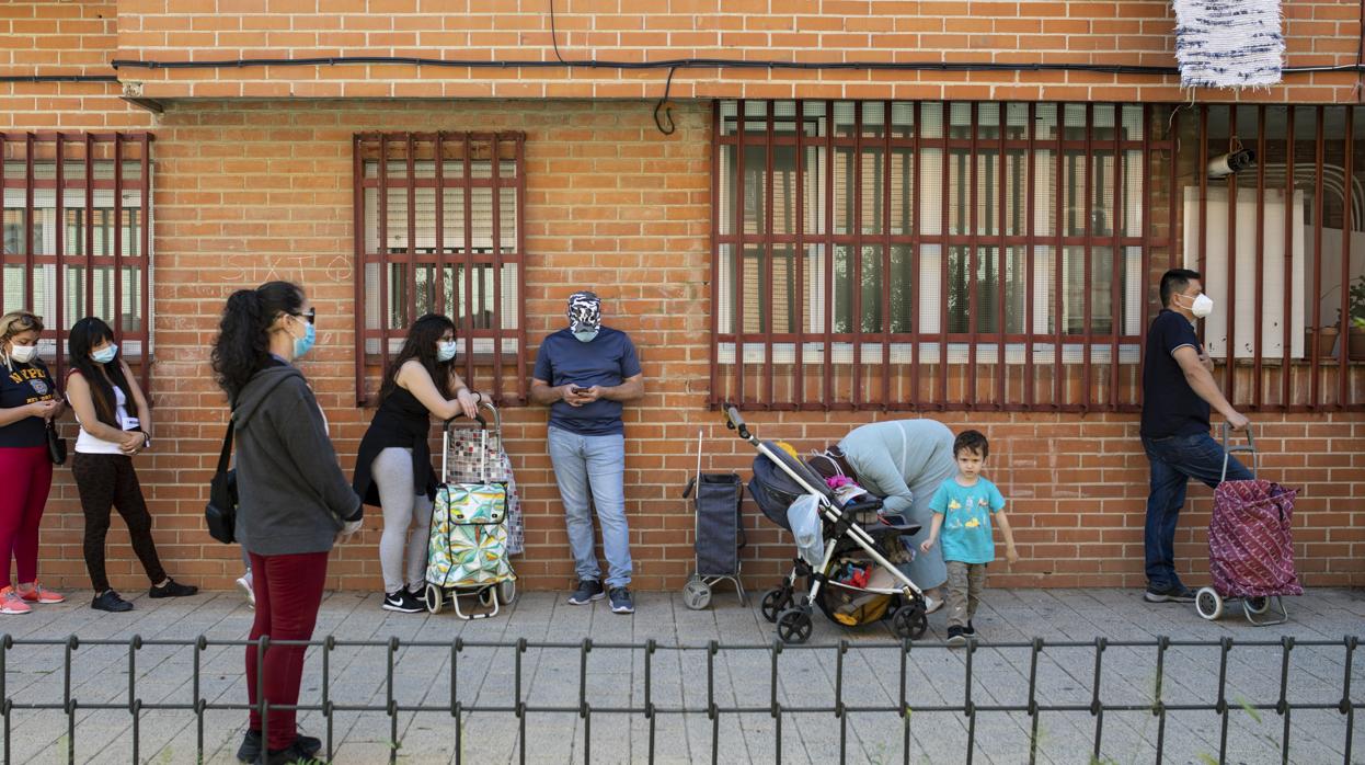 Varias personas hacen cola frente a la parroquia de San Juan de Dios, en Vallecas