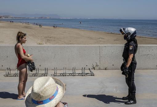 Una agente de la Policía Nacional conversa con una mujer en la playa del Cabanyal