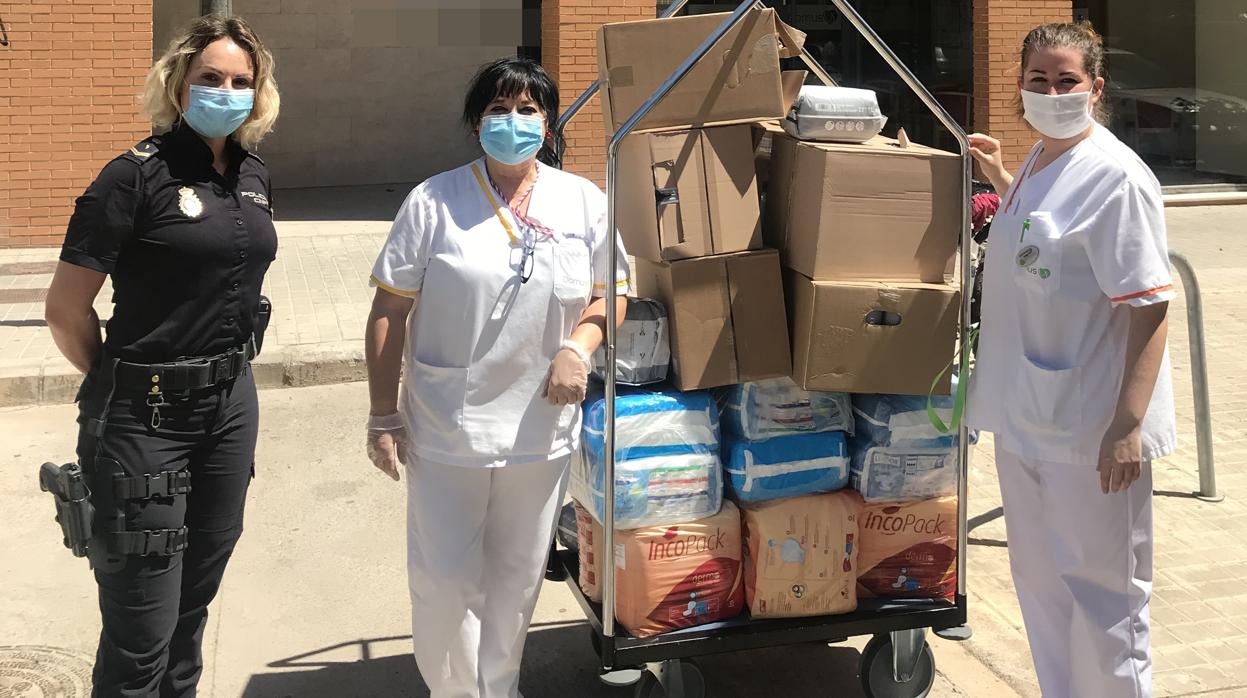 Una agente y personal de la farmacia de Valencia con material sanitario donado para los mayores