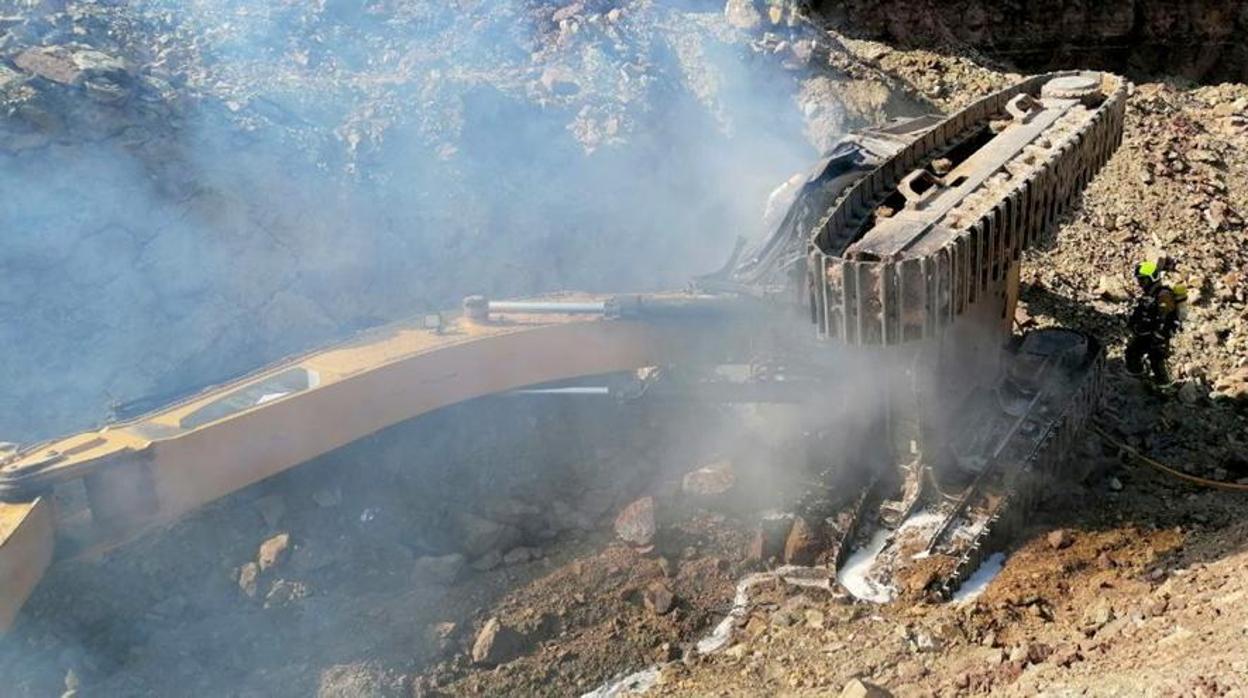 Bomberos trabajan en la extinción del fuego de la máquina excavadora, tras el accidente