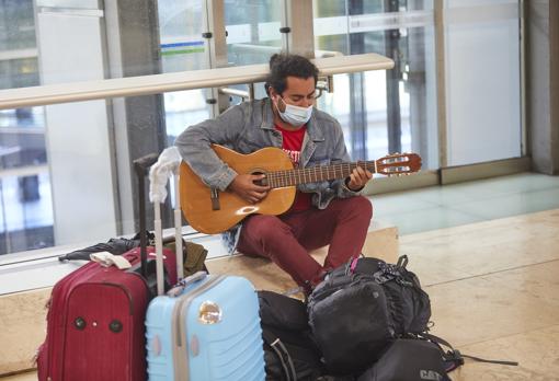 Héctor Valdivia, junto a su inseparable guitarra, espera el vuelo de regreso a Chile