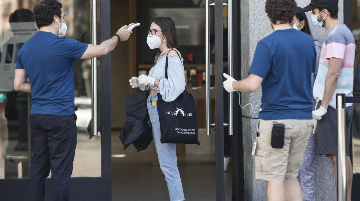 Un trabajador de Apple, en Sol, toma la temperatura, ayer, a una clienta