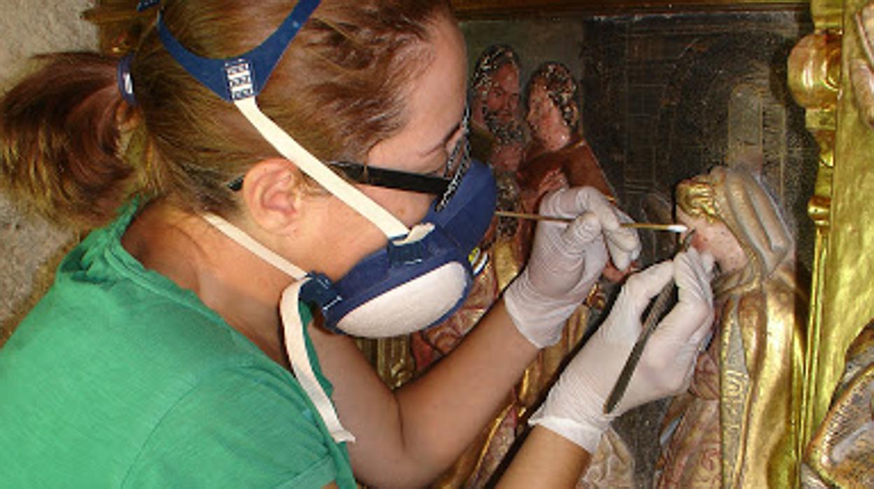 Una especialista trabajando en la restauración de un retablo policromado